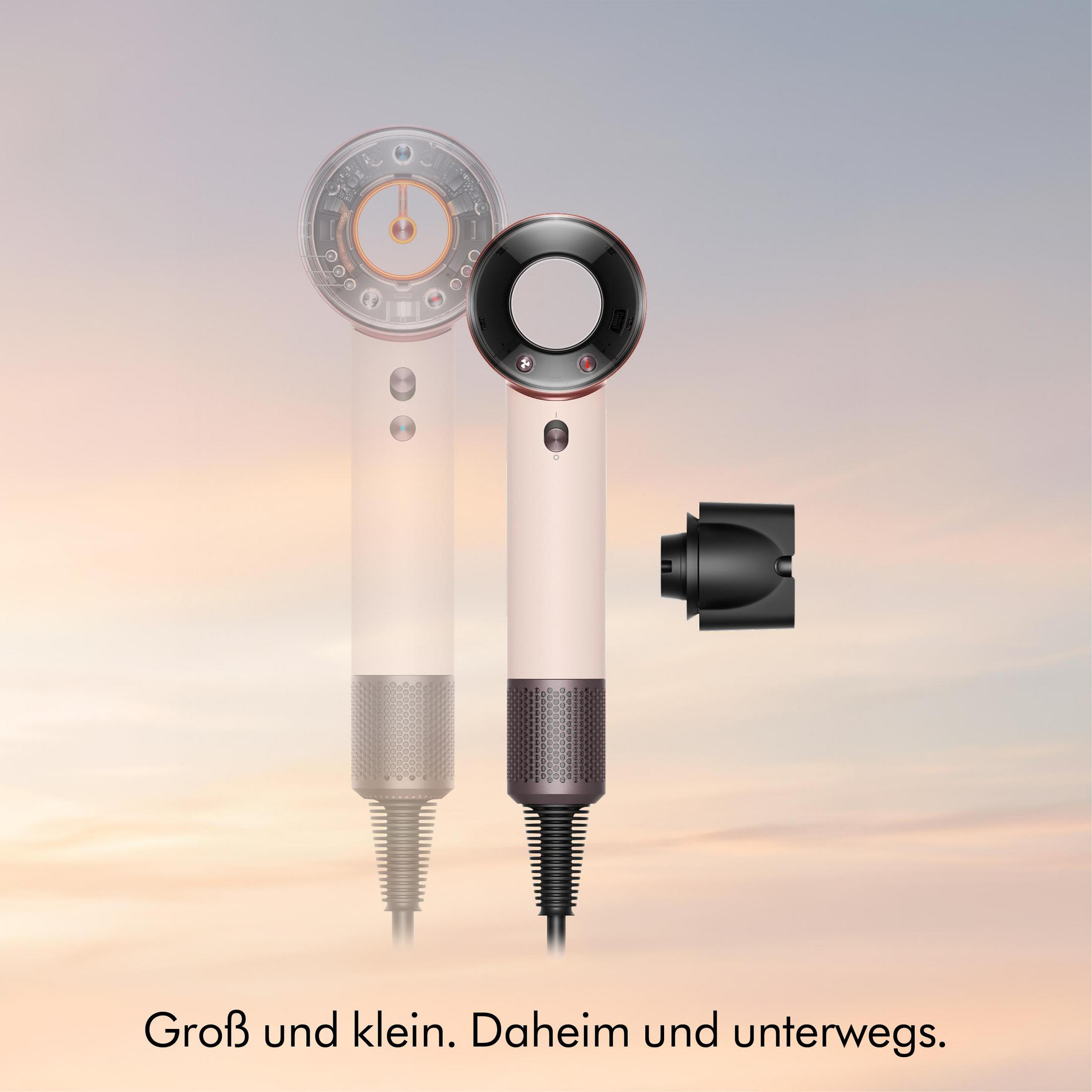 Ein rosa Haartrockner mit schwarzem Aufsatz und ein schemenhafter dryer im Hintergrund.
