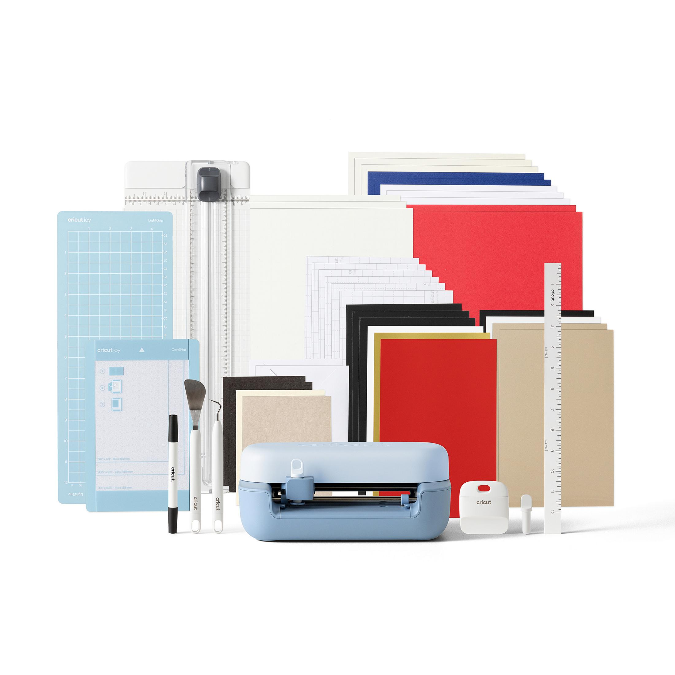 Una máquina Cricut Joy azul claro con suministros de manualidades variados como papel, tapetes y herramientas.