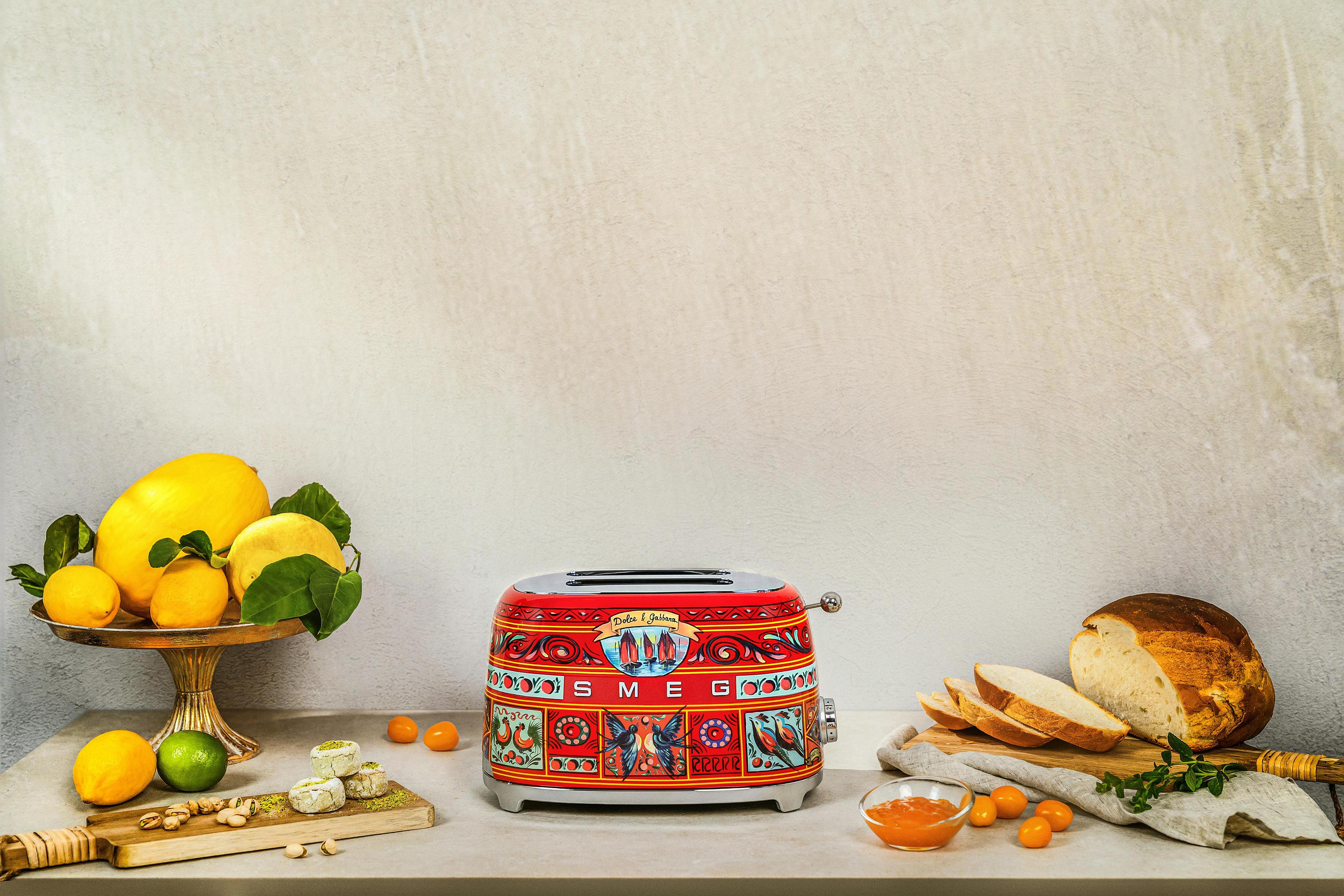 Rot-weißer Toaster mit Dolce & Gabbana-Dekor, Früchte, Brot und Marmelade.