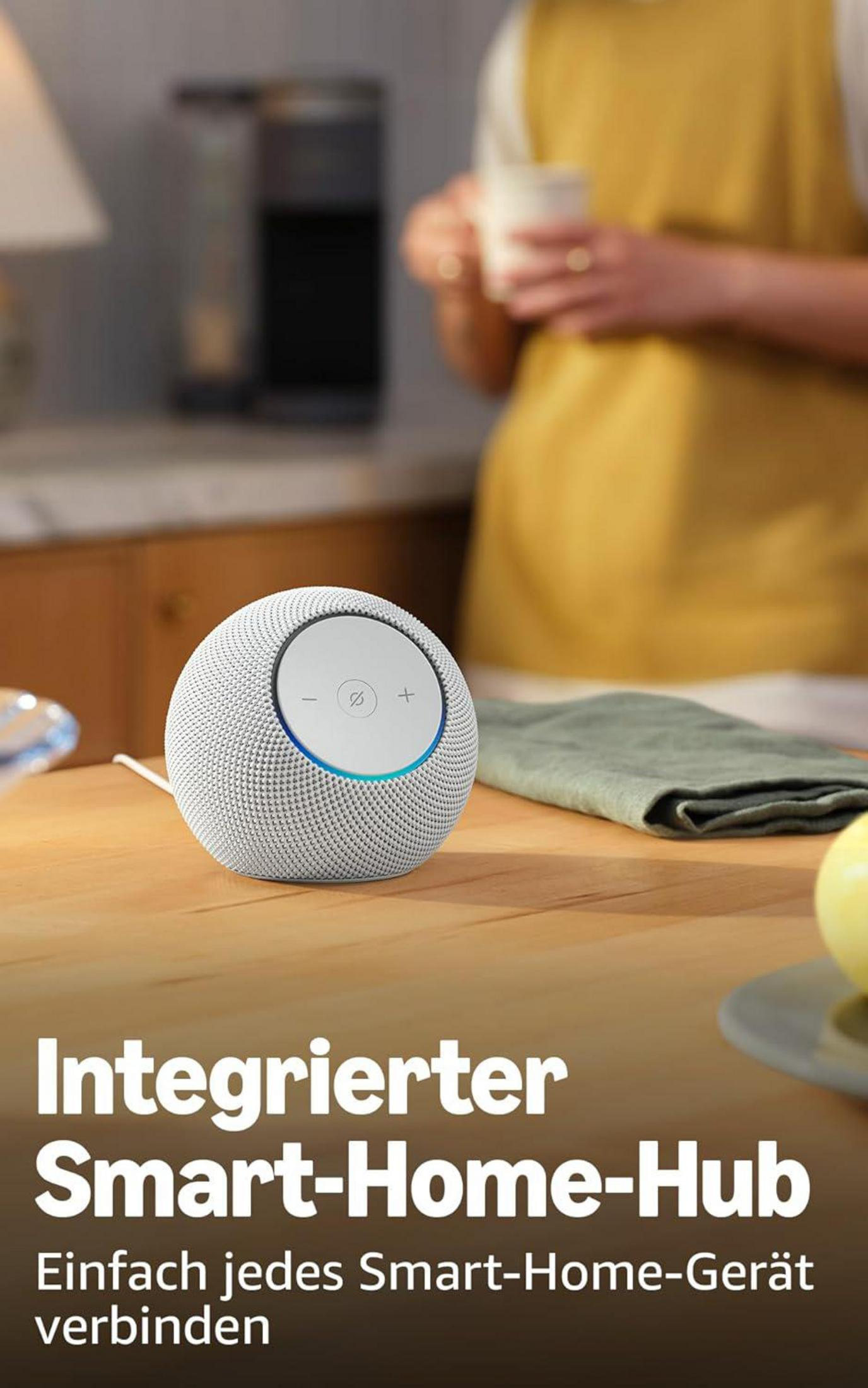 Ein weißer Smart Speaker steht auf einem Holztisch. Textüberlagerung.