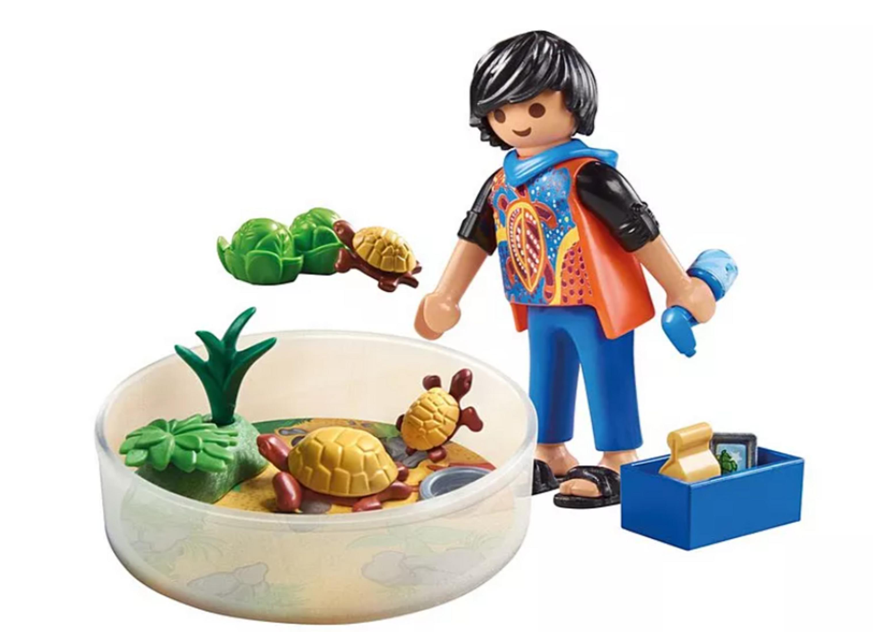 Un niño juega con tortugas en un recinto, sosteniendo una botella rociadora.