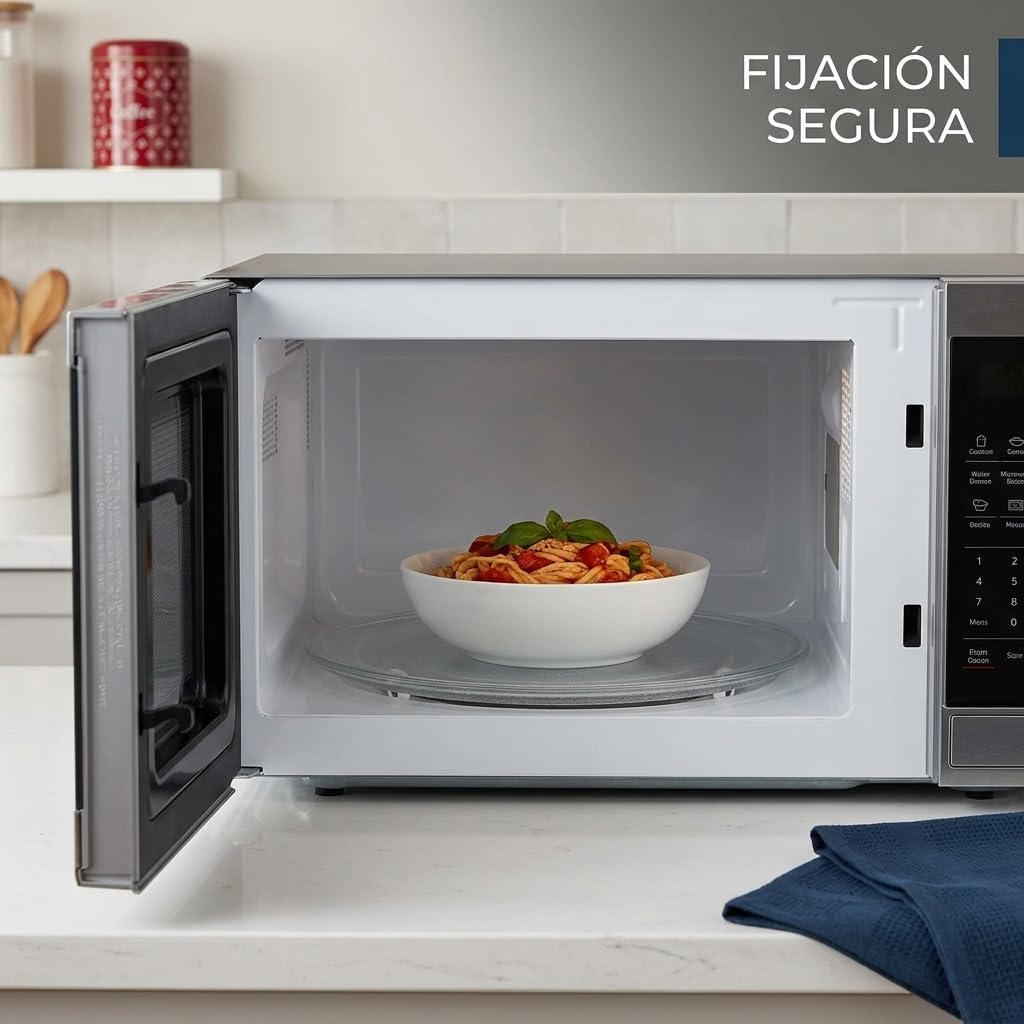 Un tazón de pasta con salsa de tomate dentro de un microondas abierto.