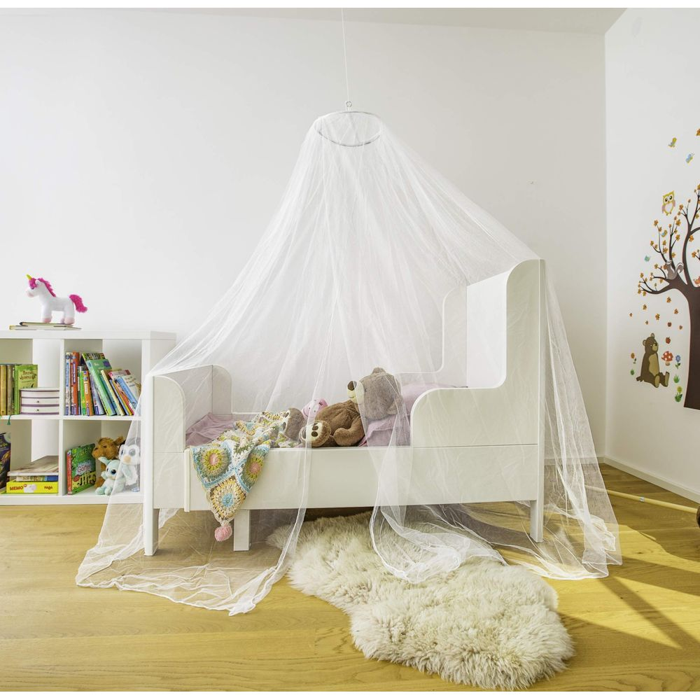 Un lit d'enfant blanc avec une moustiquaire, des ours en peluche et une couverture.