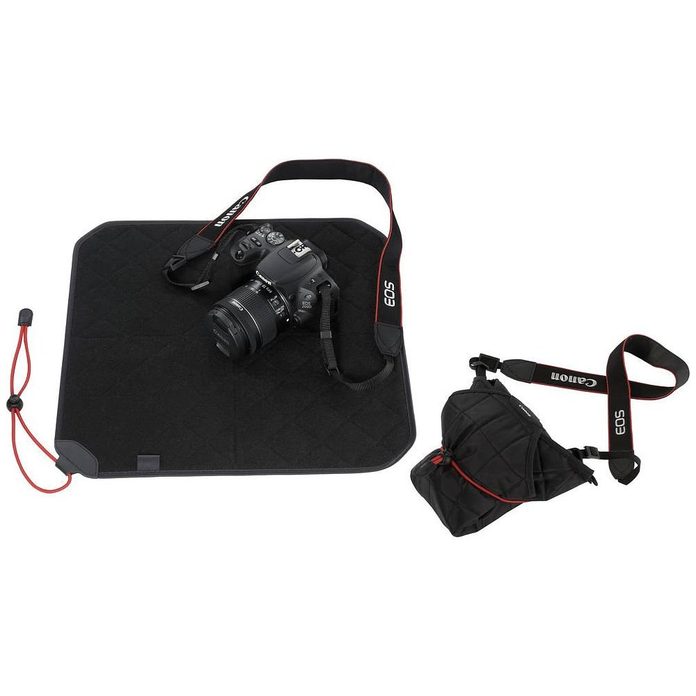 Una borsa per fotocamera nera e una fotocamera DSLR con tracolla poggiano su un tappetino nero.