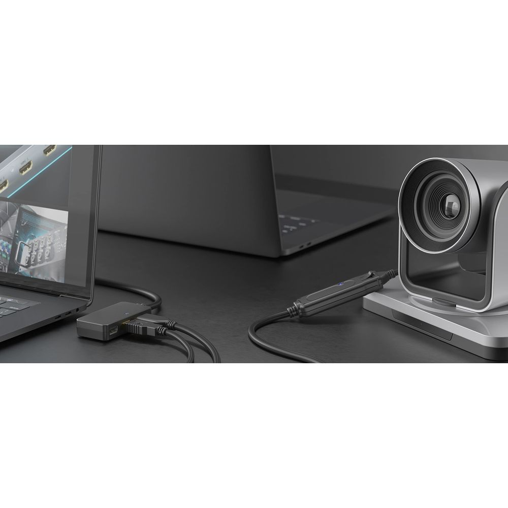 Grauer Laptop mit Adapter, Kamera und Kabeln auf schwarzer Oberfläche.