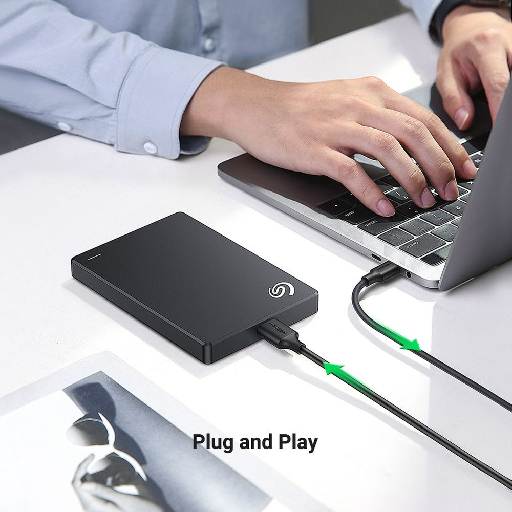 Una persona collega un hard disk esterno nero a un laptop.