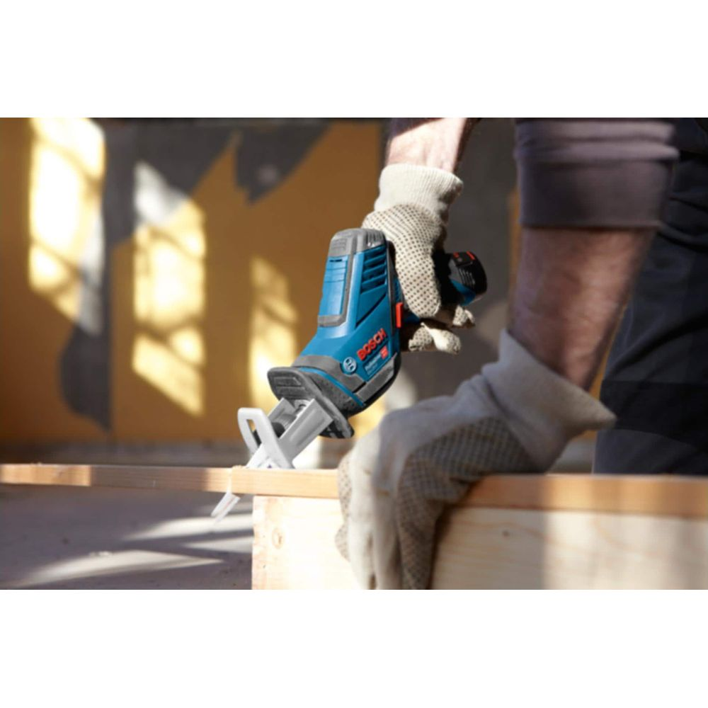 Een hand met handschoenen houdt een blauwe Bosch reciprozaag vast die hout zaagt.