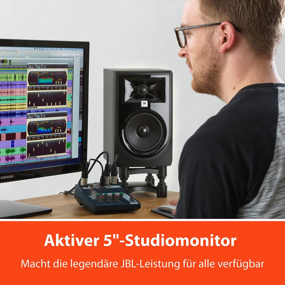 Uomo guarda monitor da studio nero, mixer e schermo del computer con forme d'onda.