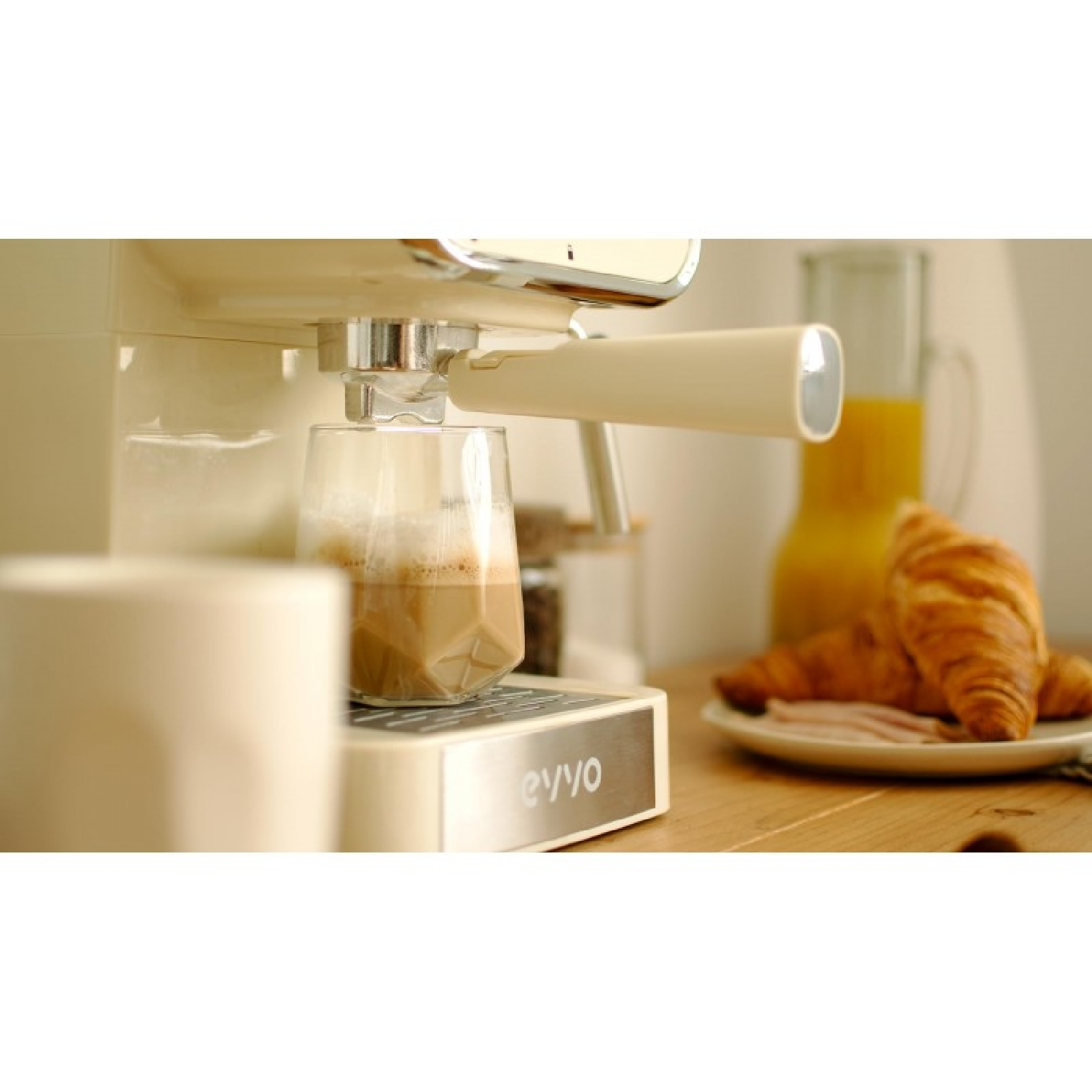 Máquina de espresso preparando café en vaso. Croissants y jamón en plato.