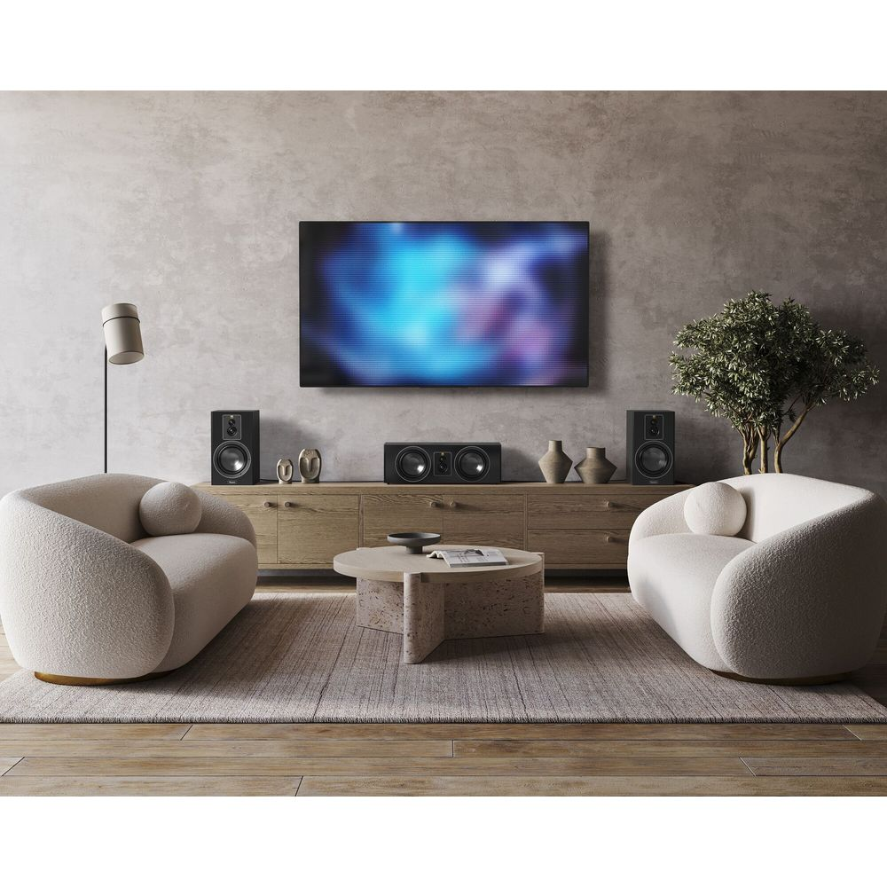 Ein Wohnzimmer mit zwei Sesseln, einem Couchtisch, einem TV und Lautsprechern.