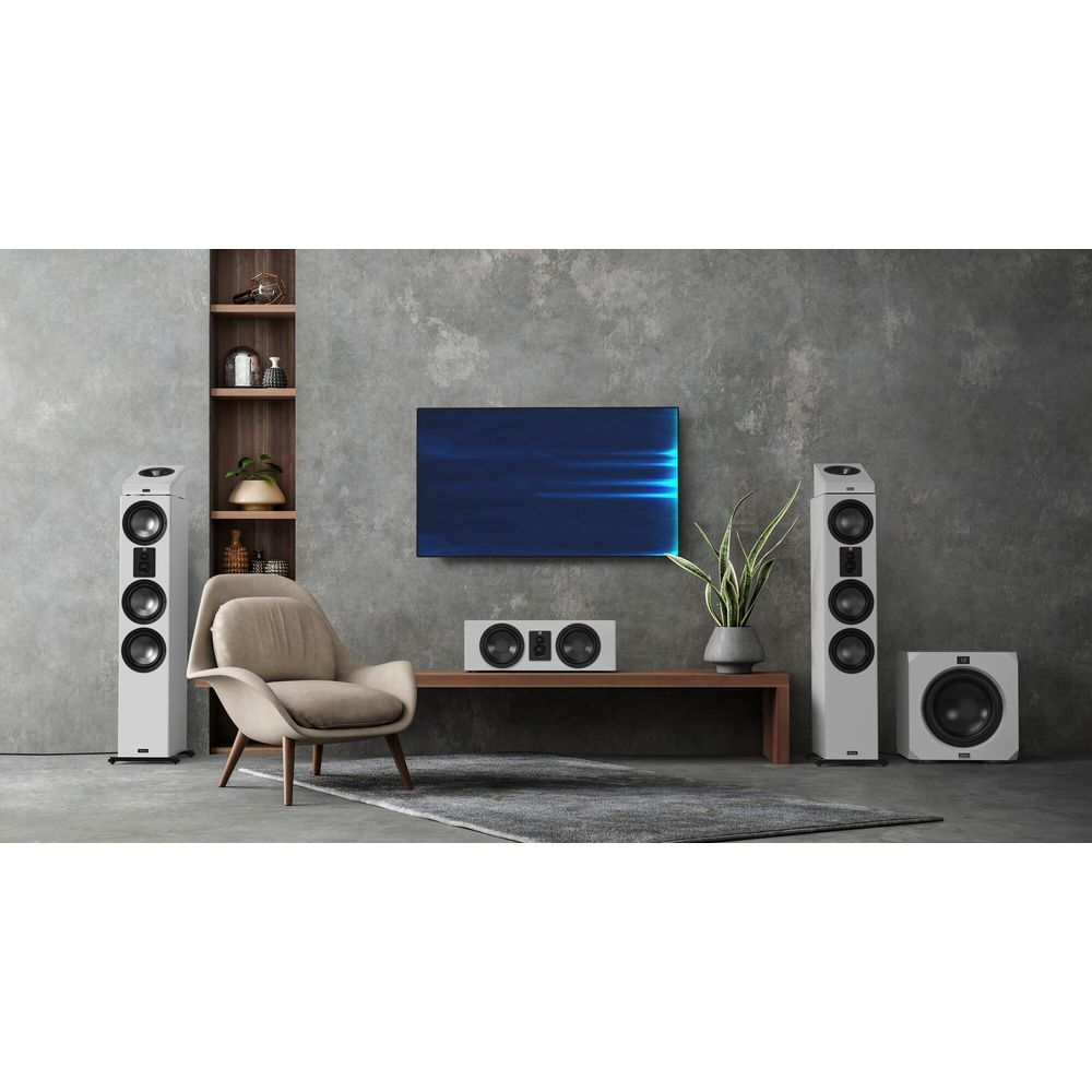 Ein modernes Wohnzimmer mit zwei weißen Standlautsprechern, einem Subwoofer, einem Fernseher und einem Sessel.