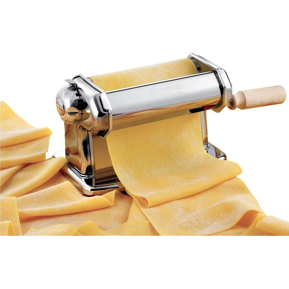 Una macchina per pasta argentata con manico in legno e pasta appena arrotolata.