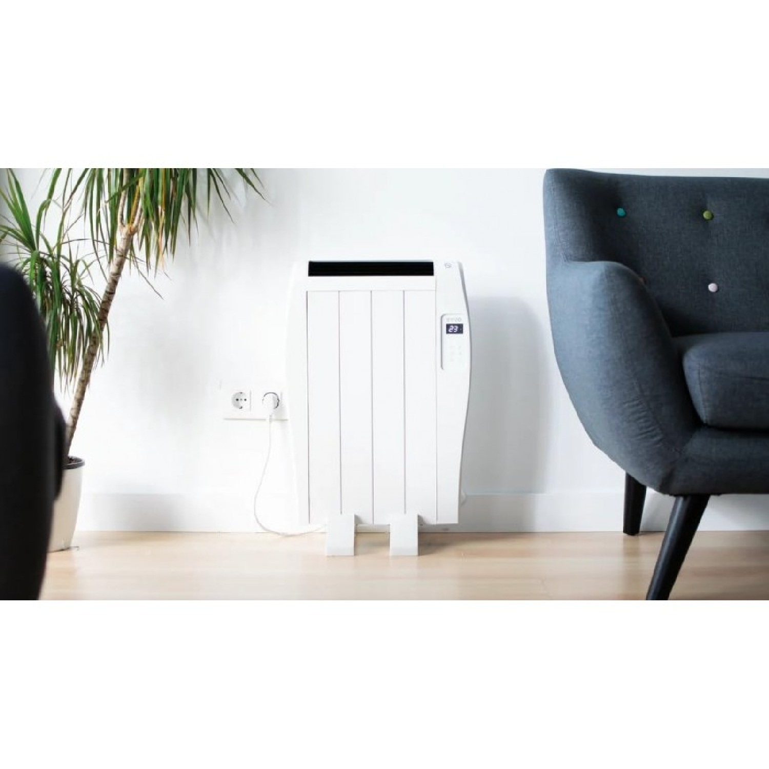 Un radiador blanco junto a un sillón y una planta.