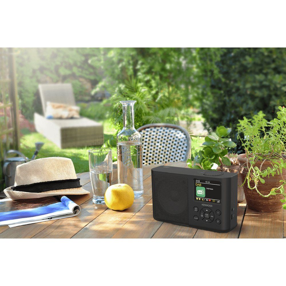 Mesa exterior con radio, sombrero, manzana, botella de agua y vaso.