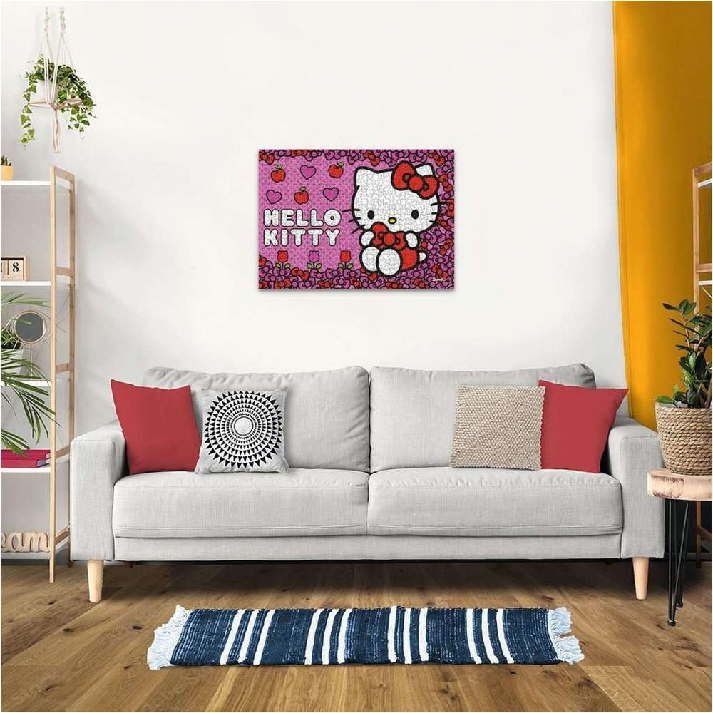Gemälde mit Hello Kitty und Äpfeln über einem Sofa mit roten und gemusterten Kissen.