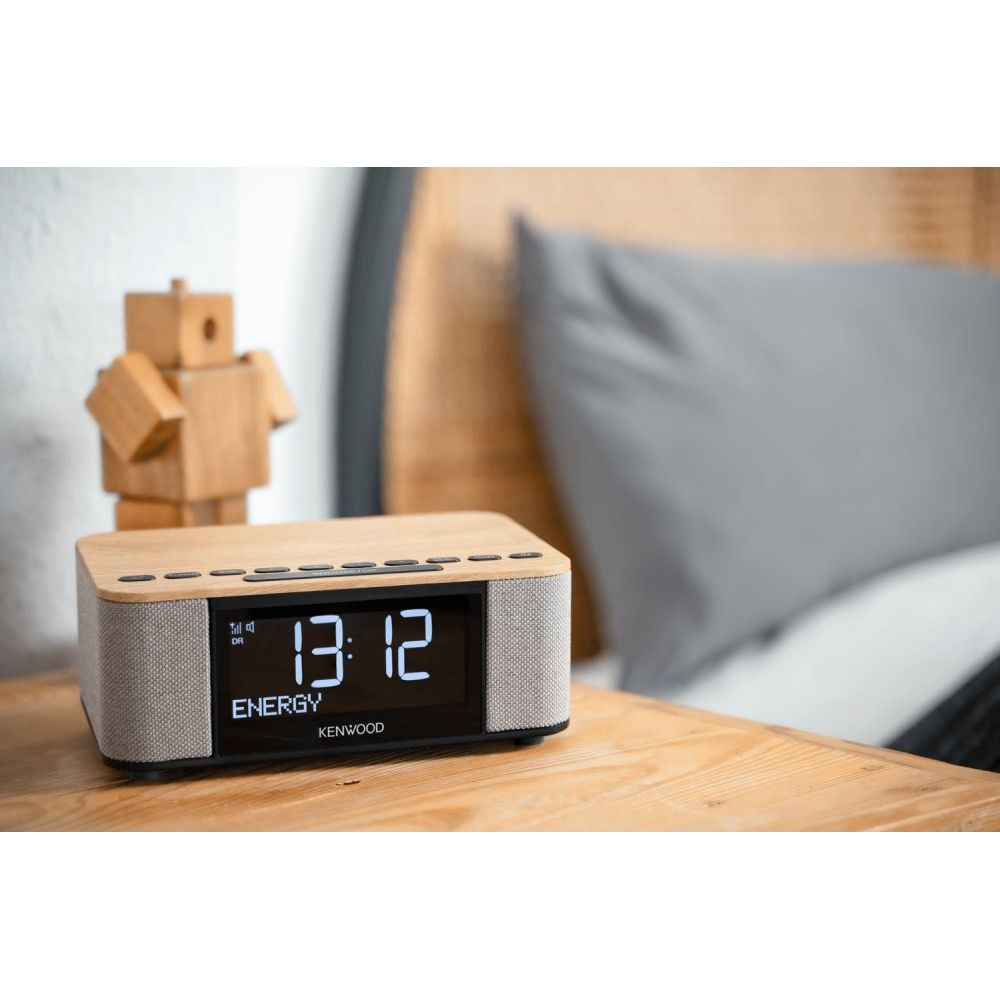 Una radio in legno con display digitale si trova sul comodino accanto a un robot di legno.
