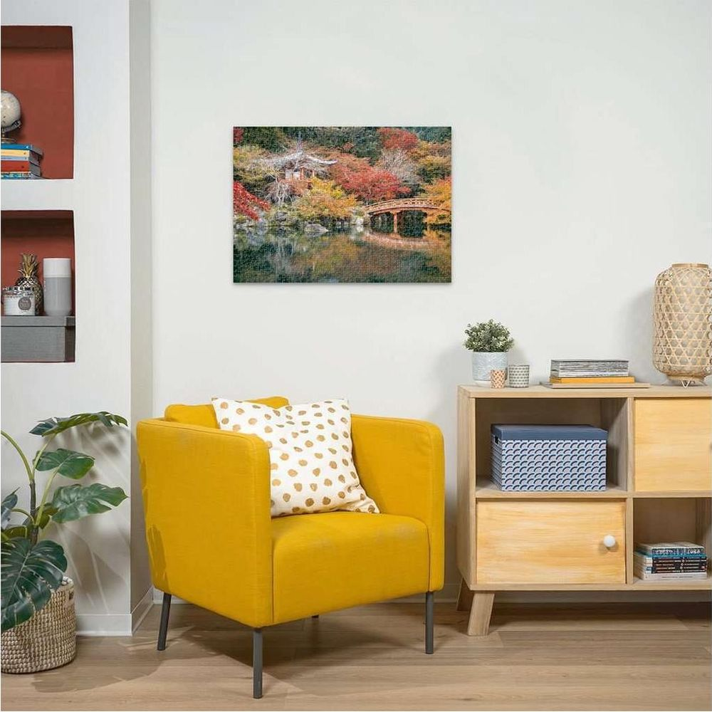 Una poltrona gialla con cuscino davanti a un mobile in legno. Un quadro di paesaggio giapponese è appeso al muro.