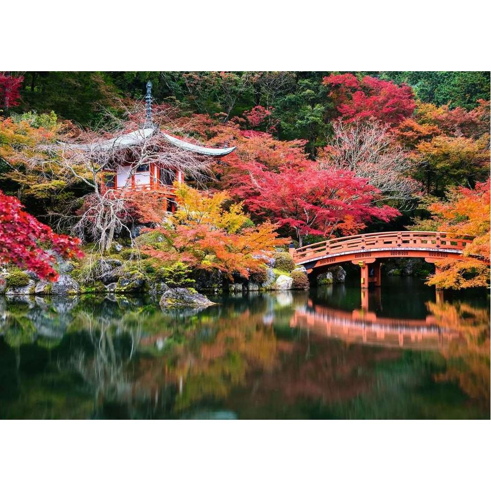 Un tempio giapponese con un ponte rosso su uno stagno, circondato da fogliame autunnale.
