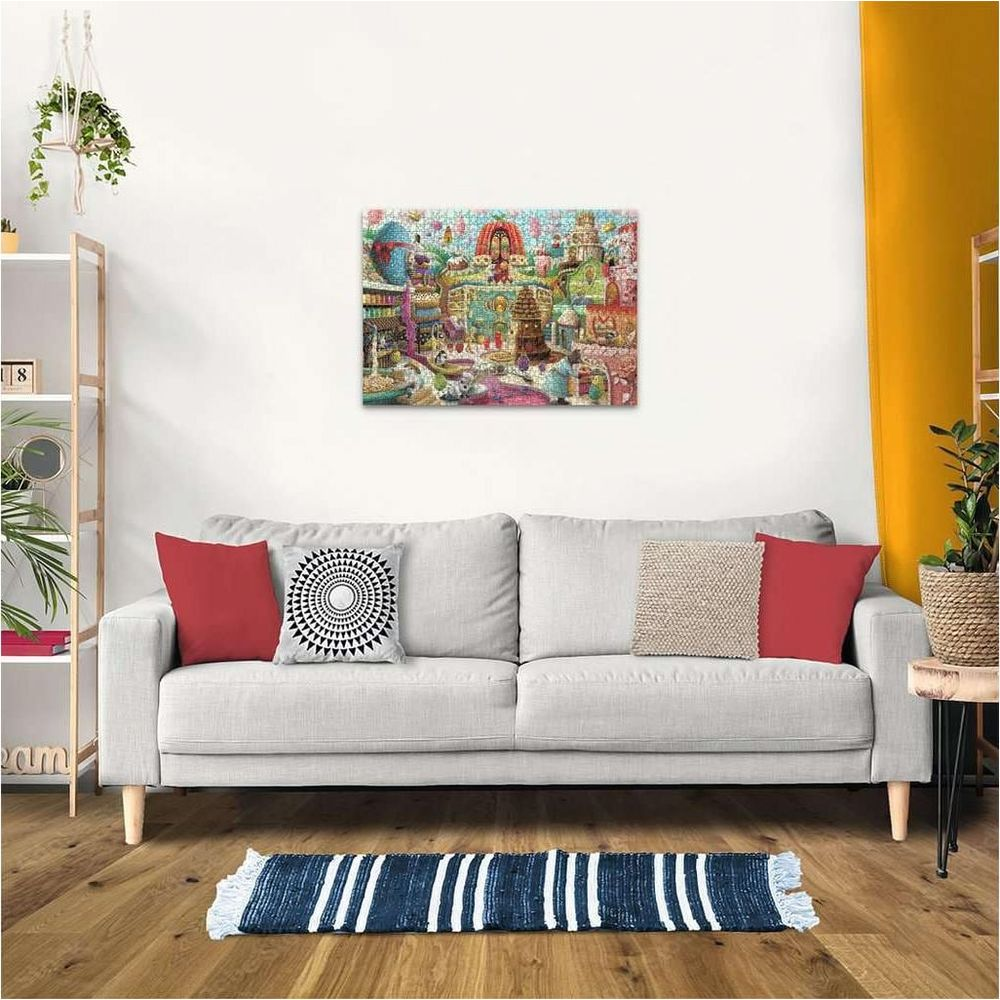 Un colorato puzzle raffigurante un paesaggio urbano dettagliato è appeso a una parete bianca sopra un divano.