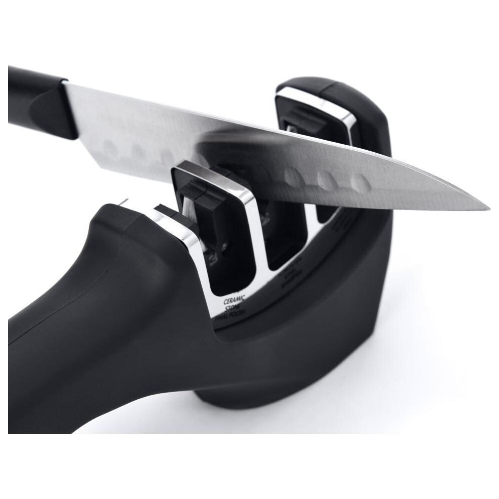 A kitchen knife is being sharpened in a black knife sharpener.