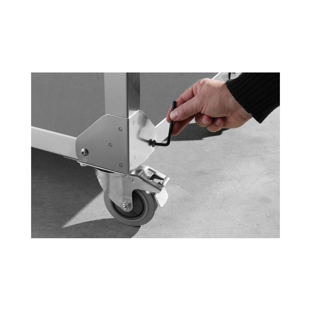 Una mano usa una chiave esagonale per serrare una ruota su un carrello metallico con rotelle.