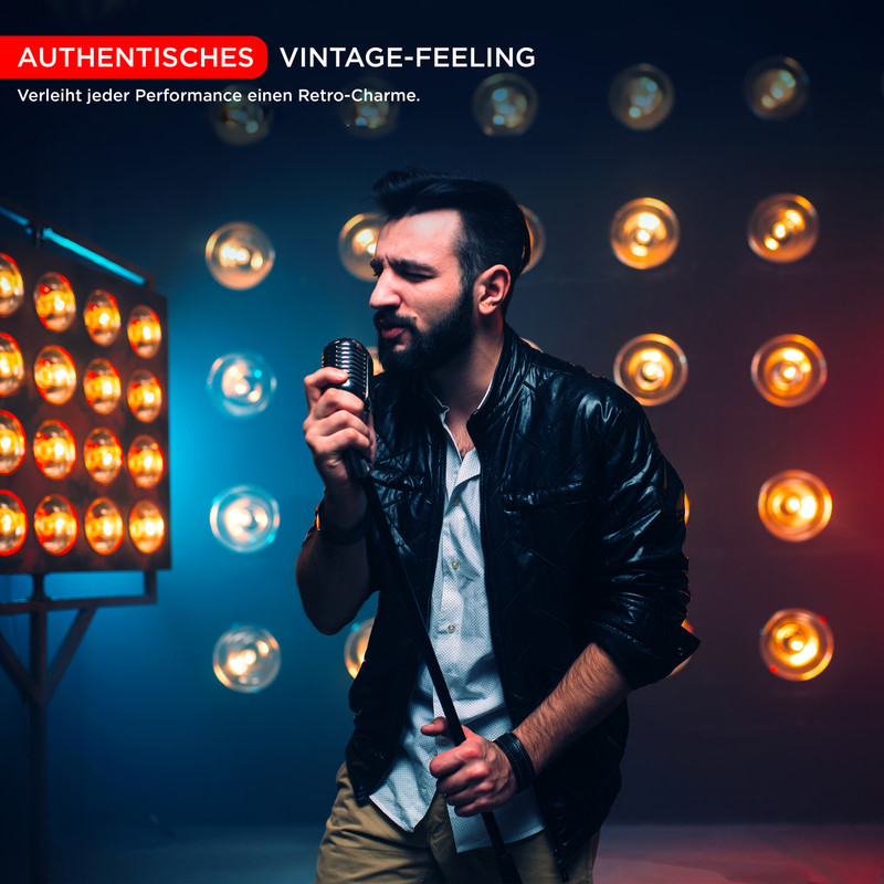 Ein Mann mit Bart singt in ein Retro-Mikrofon vor Lichtern.