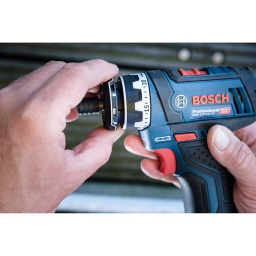 Une main ajuste un outil Bosch bleu avec un foret. Gros plan.