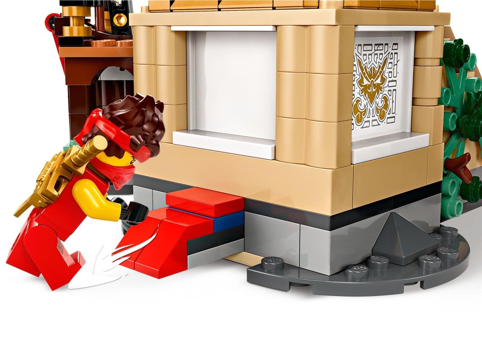 Ein Lego-Charakter in Rot mit goldenem Rucksack klettert auf rote Stufen vor einem Gebäude.