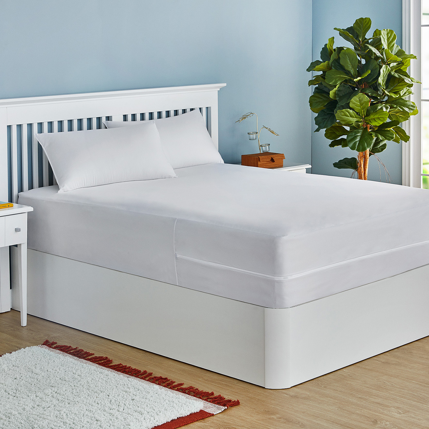Una cama blanca con dos almohadas, cubierta con un cubrecama blanco.