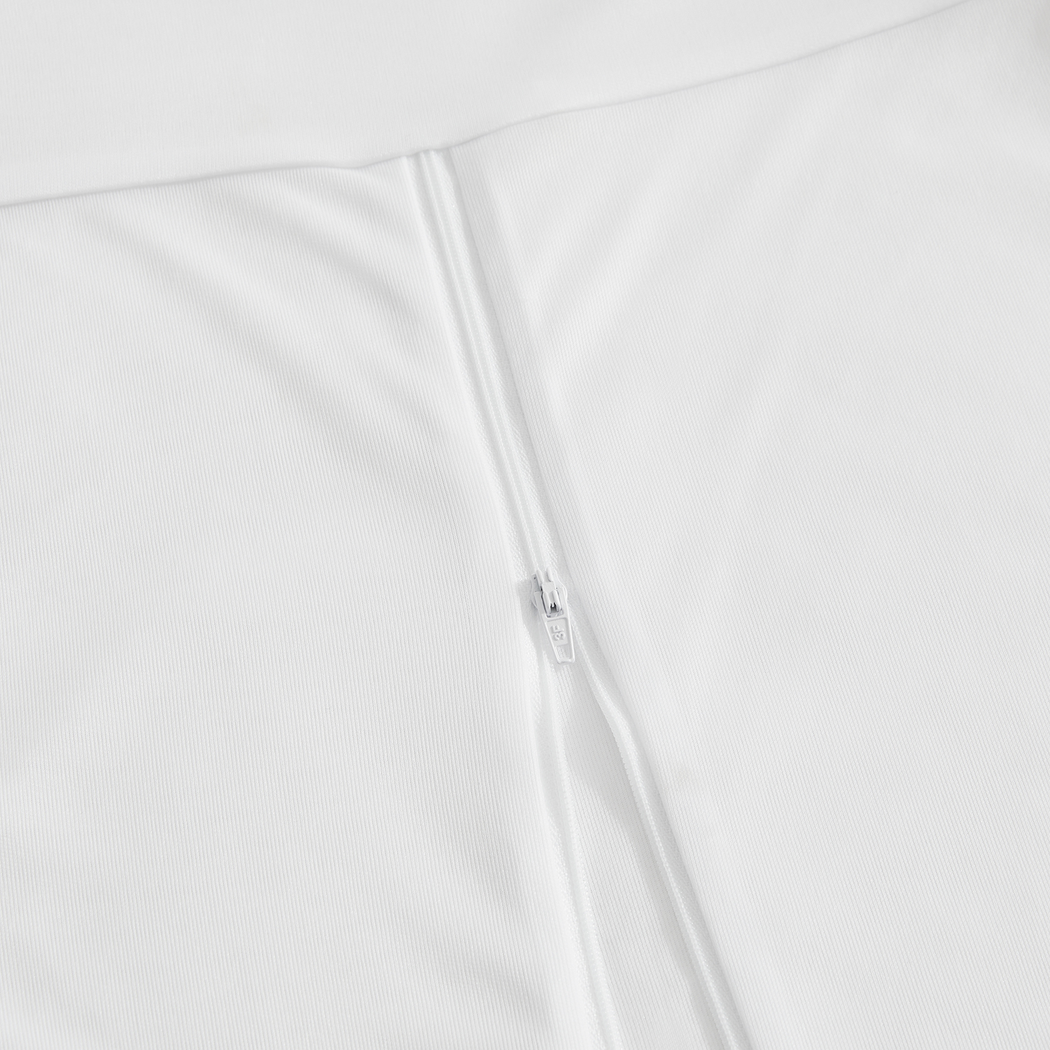 Primer plano de una cremallera blanca sobre tela blanca.