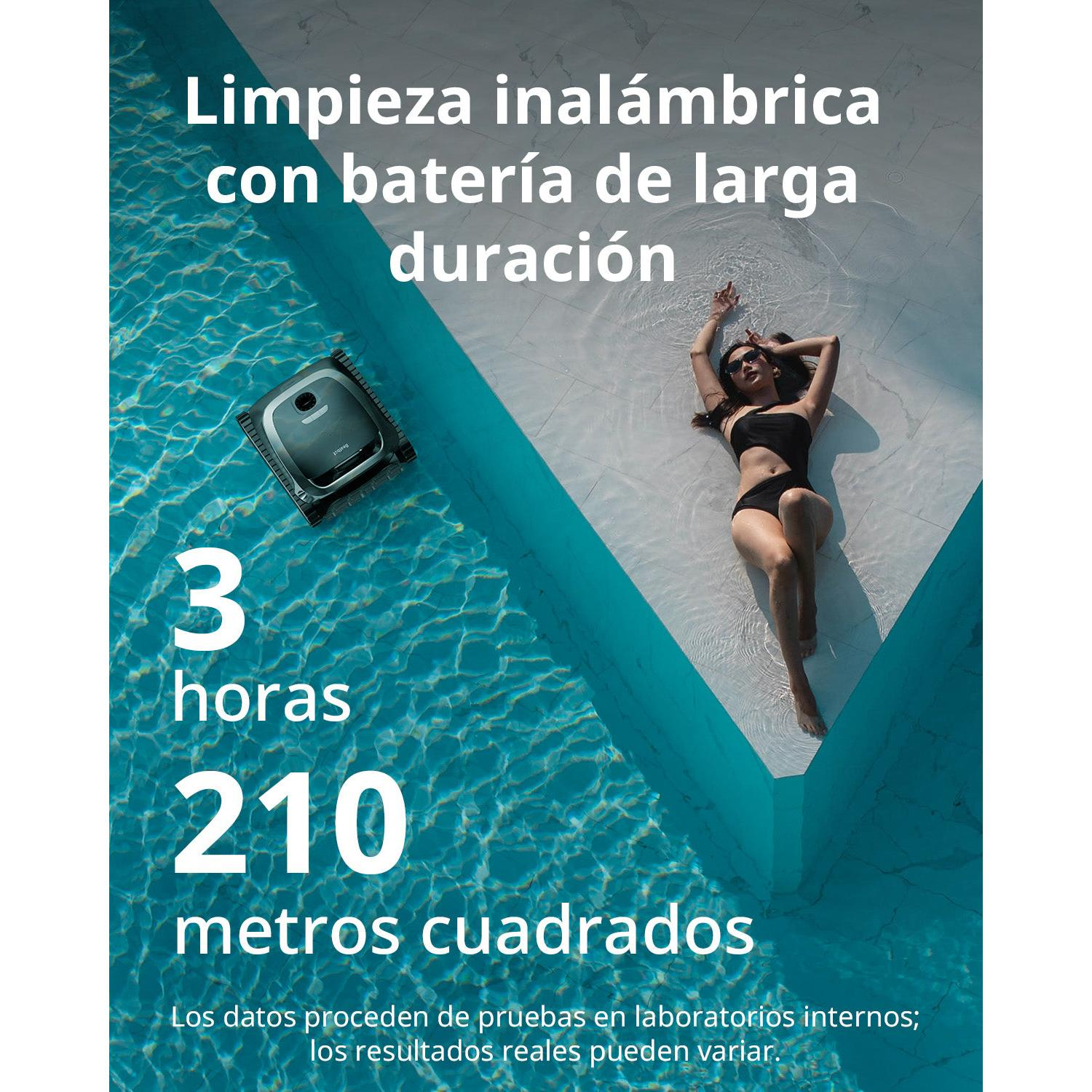 Un limpiafondos opera en una piscina, con una mujer tomando el sol cerca.