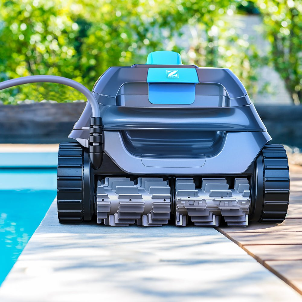 Un robot de piscina gris con detalles azules se sienta en una terraza de madera junto a la piscina.