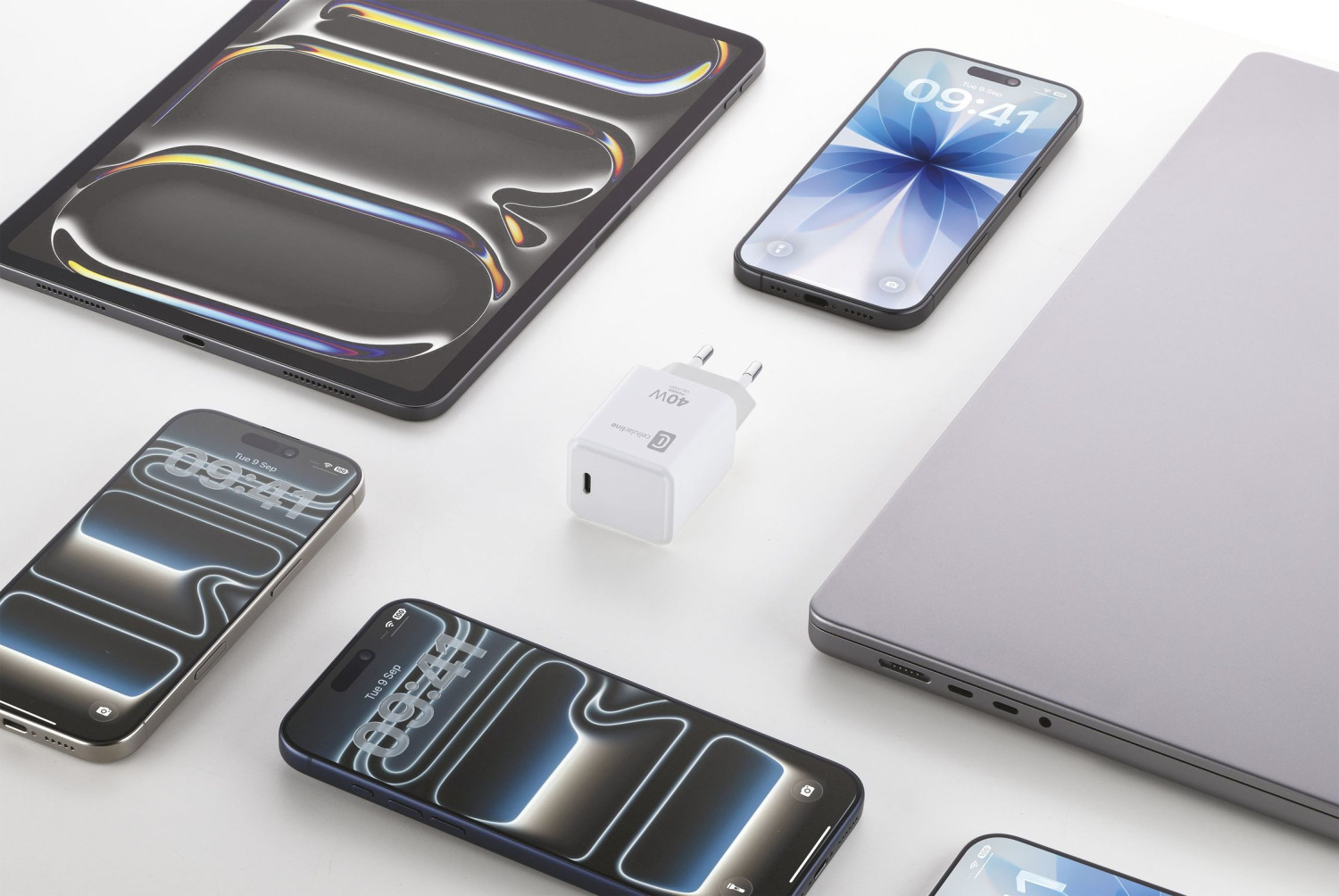 Drei iPhones, ein Tablet, ein Ladegerät und ein Laptop auf weißem Hintergrund.