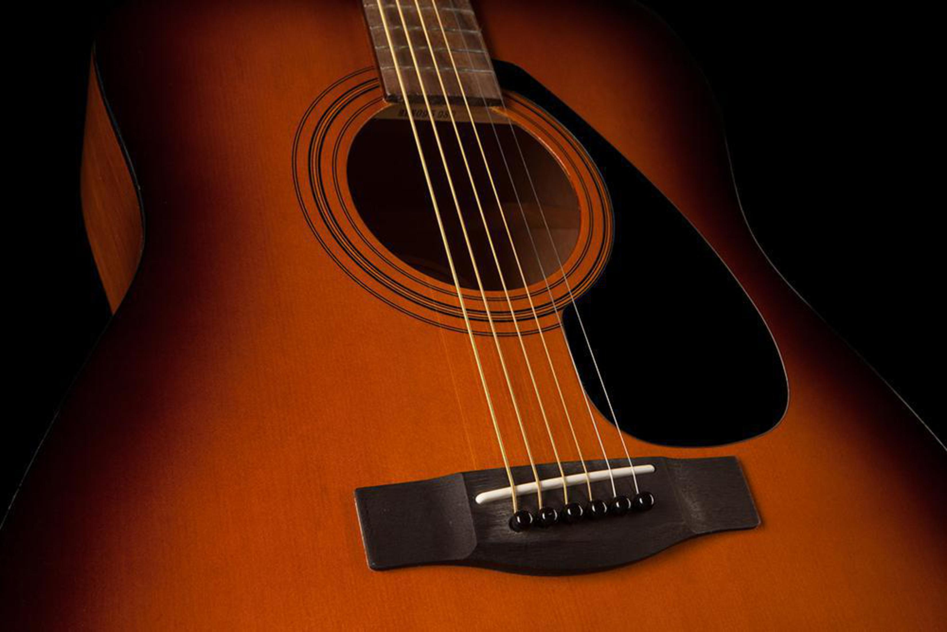 Eine braune Akustikgitarre mit sechs Saiten, Nahaufnahme.