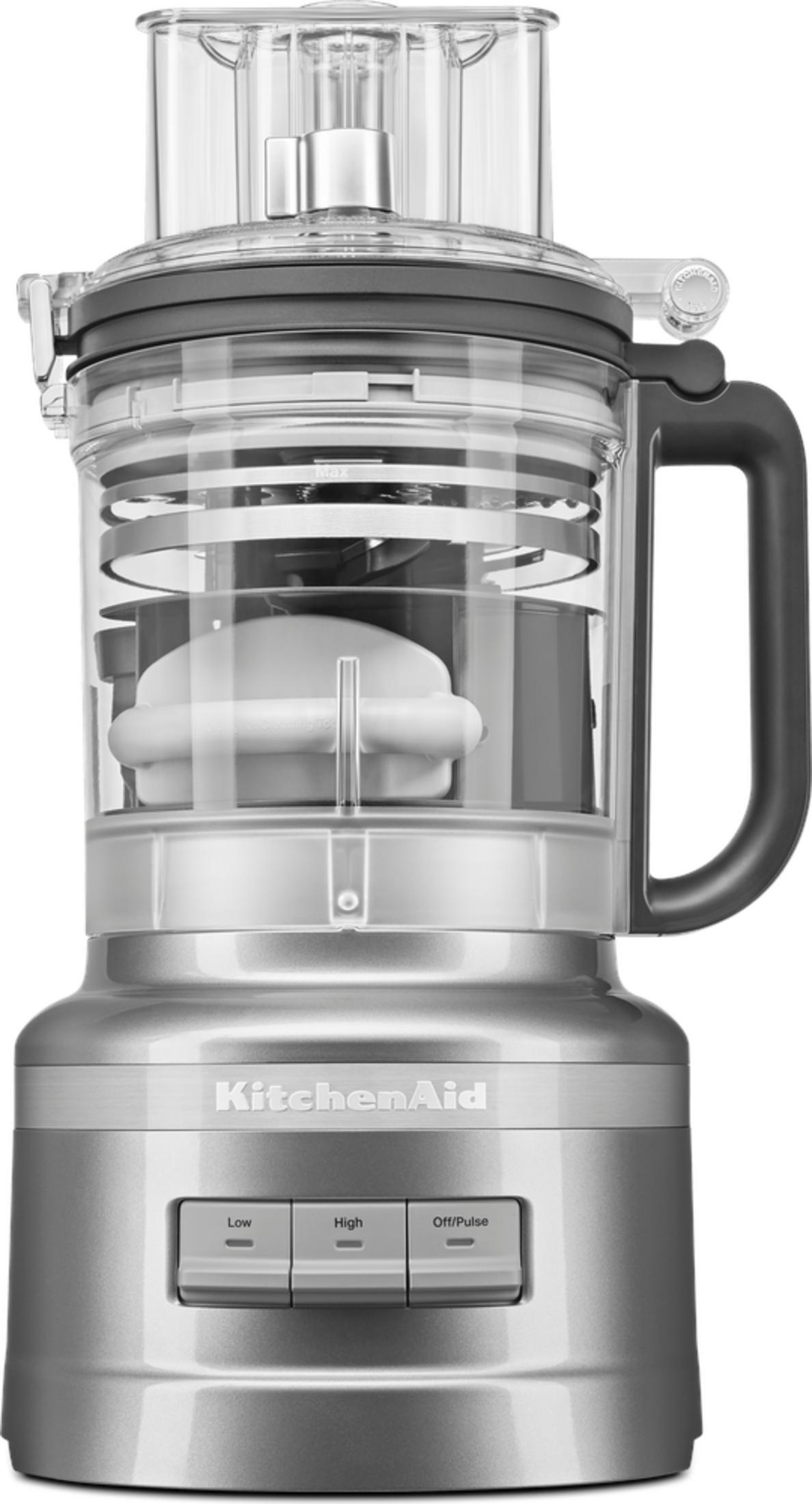 Gümüş renkli KitchenAid mutfak robotu, şeffaf hazne, siyah sap ve kontrol düğmeleri.