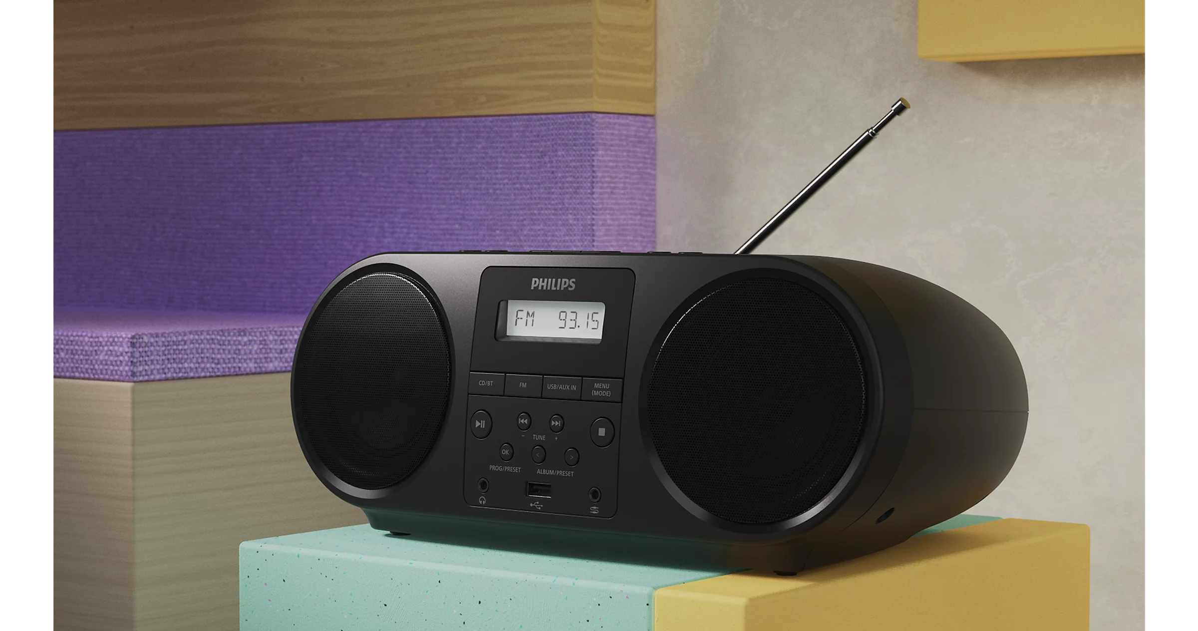 Boombox Philips nera con display FM 93.15, su blocchi colorati.