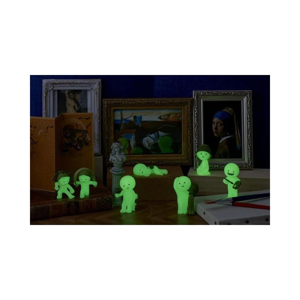 Leuchtende Figuren vor Kunstwerken und Büchern auf einem Holztisch.