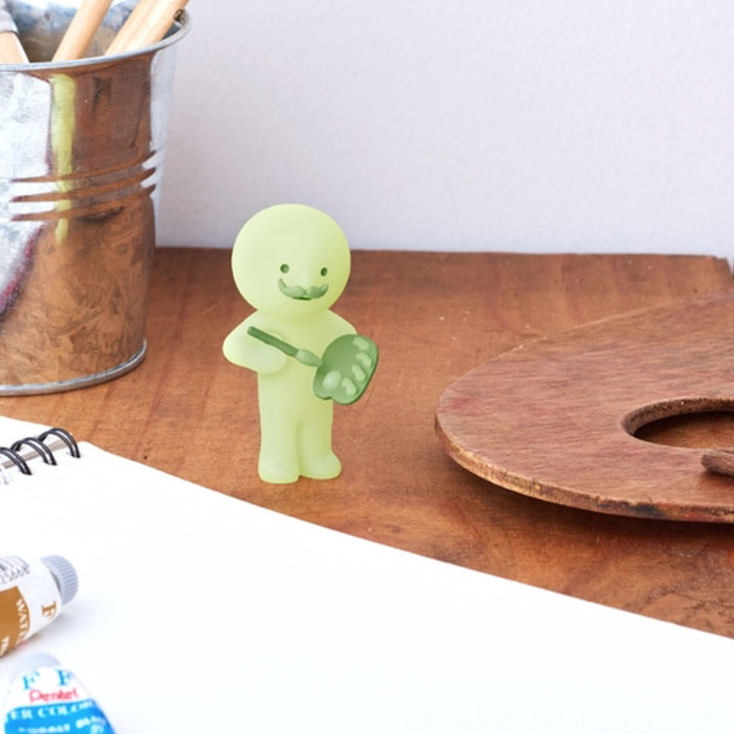 Eine durchscheinende grüne Figur mit Schnurrbart hält eine Farbpalette und einen Pinsel.