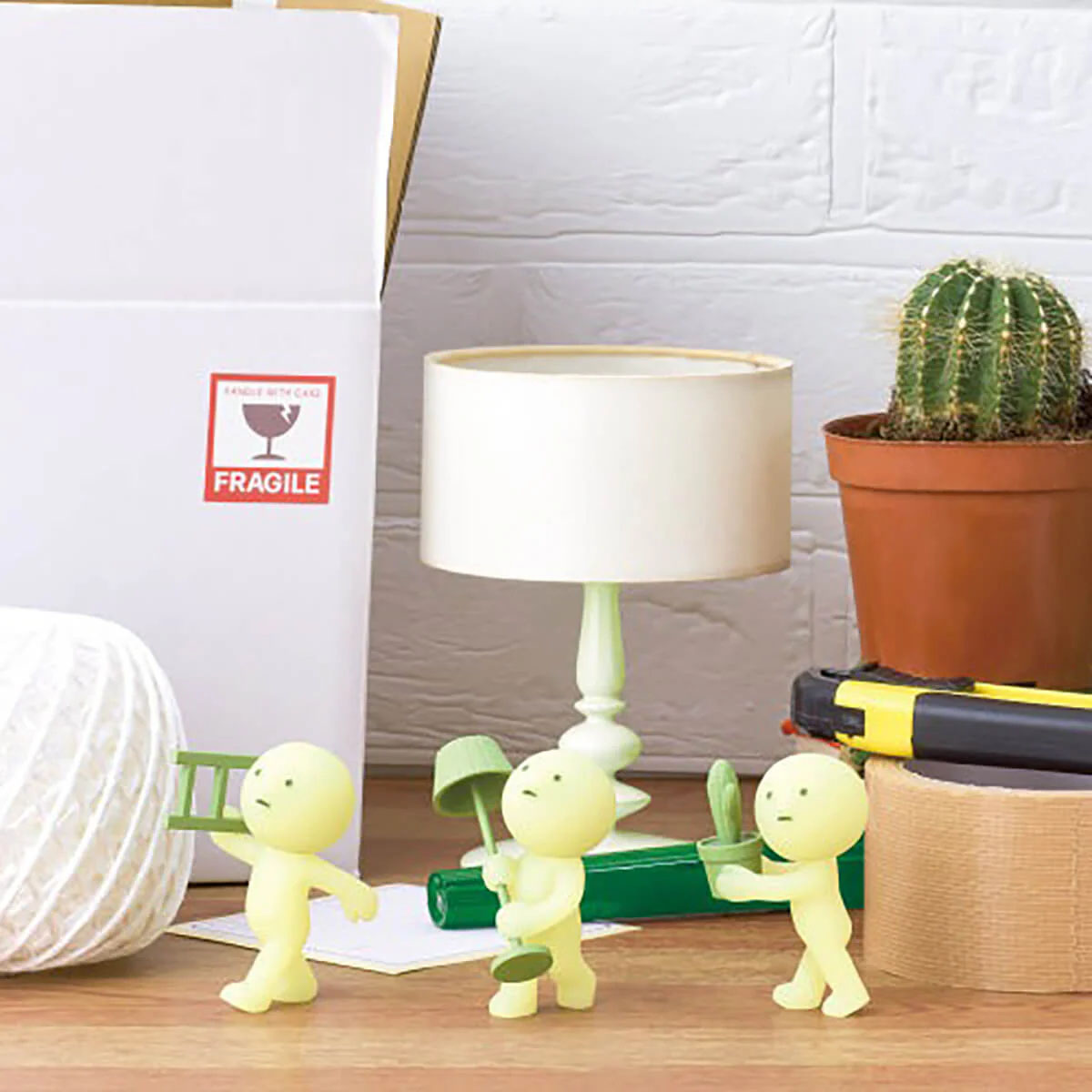 Gelbe Figuren bewegen Gegenstände: Kiste, Leiter, Lampe, Kaktus, Klebeband.