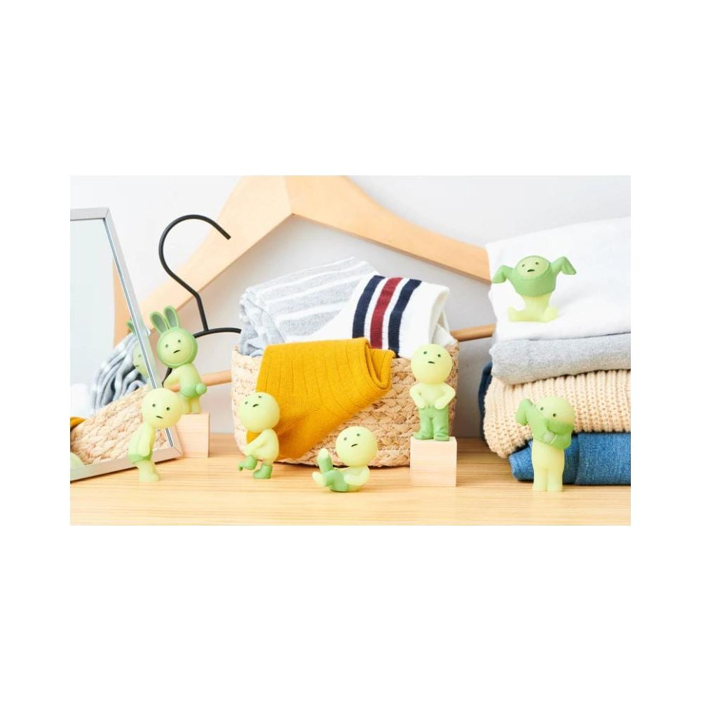 Sieben grüne Figuren stehen um einen Korb mit Kleidung und Socken.