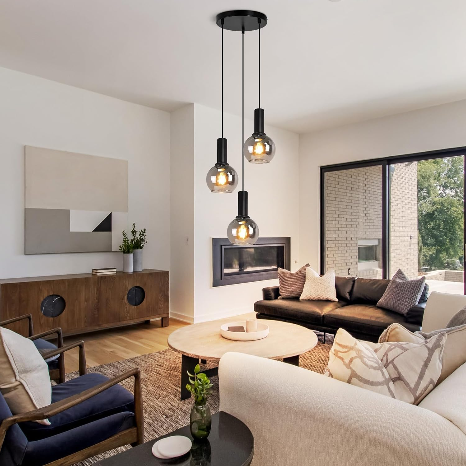 Sala de estar moderna con tres lámparas colgantes, sofá de cuero, sillones y chimenea.