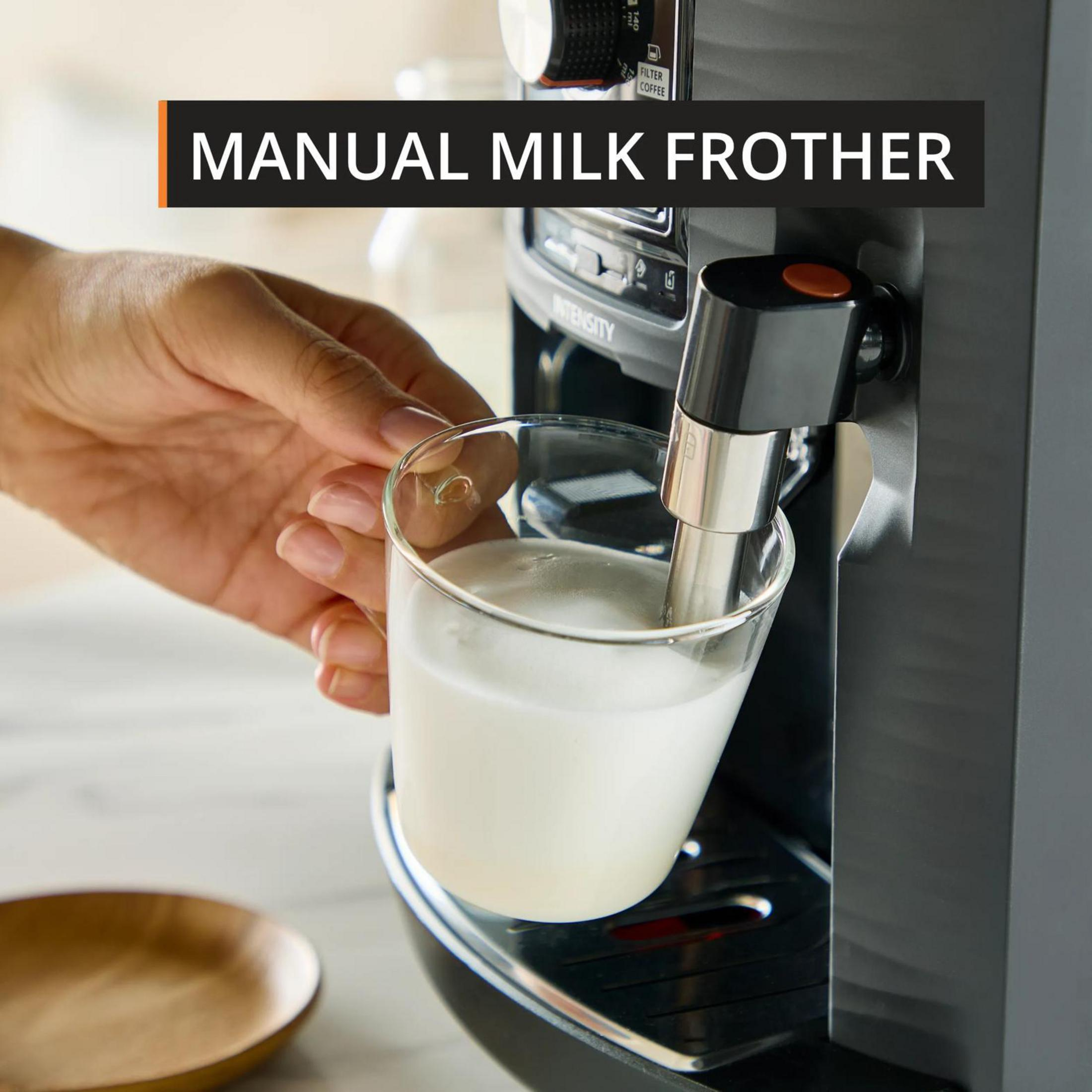 Eine Hand hält ein Glas Milch, das von einer Kaffeemaschine aufgeschäumt wird.
