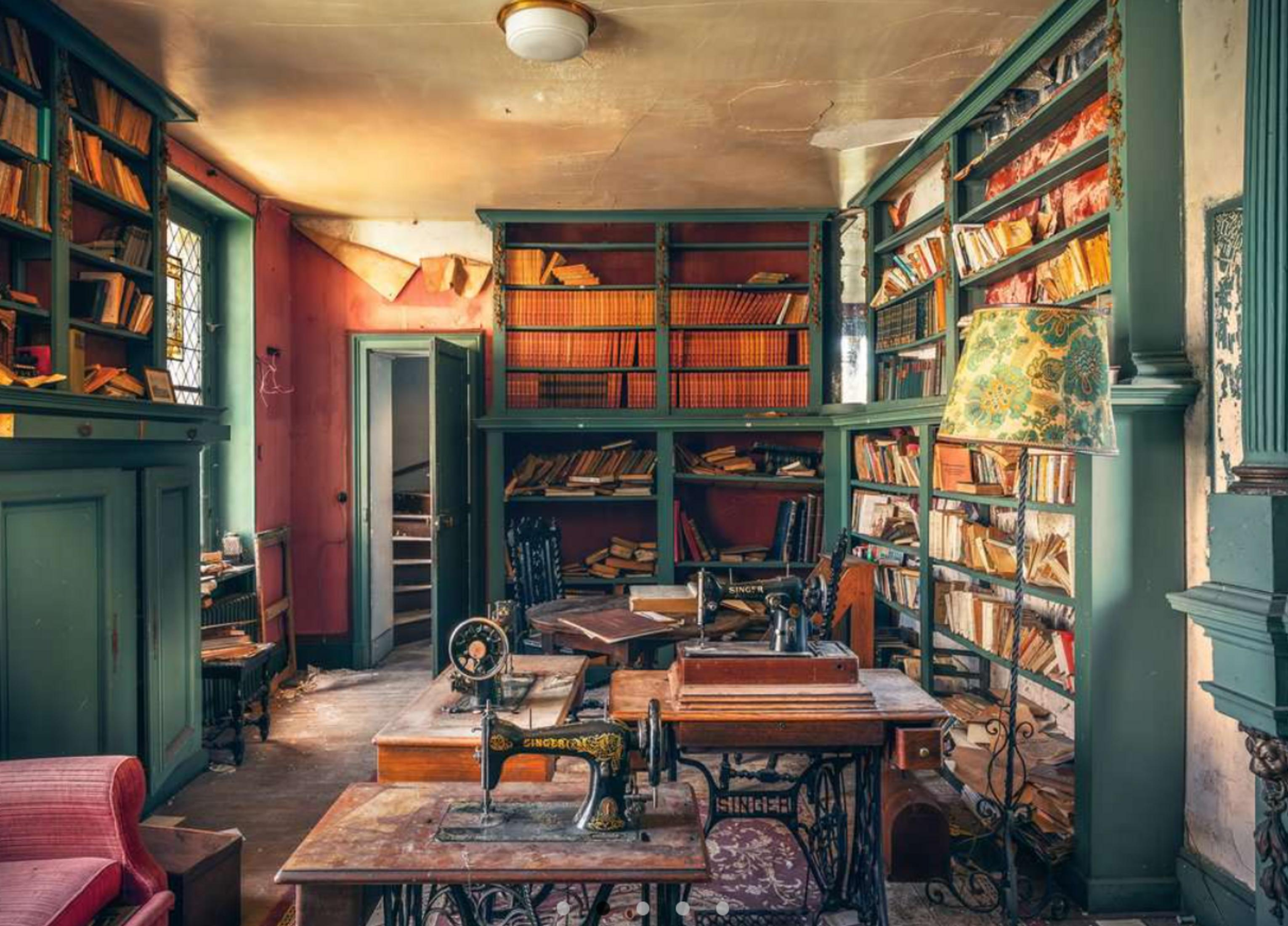 Una stanza con librerie, macchine da cucire e una poltrona rossa.