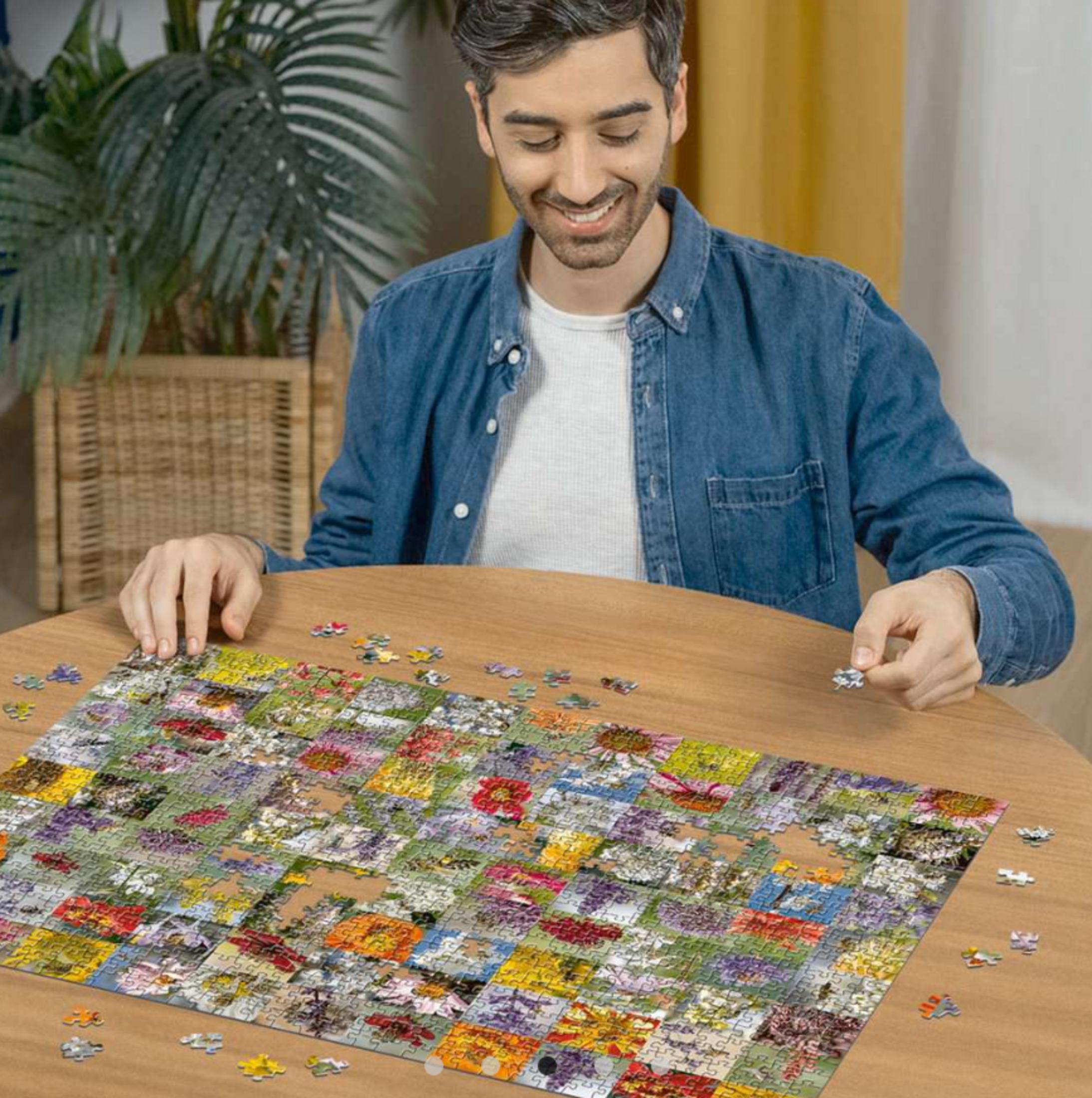 Ein Mann sitzt an einem Holztisch und vervollständigt ein Blumen-Puzzle.