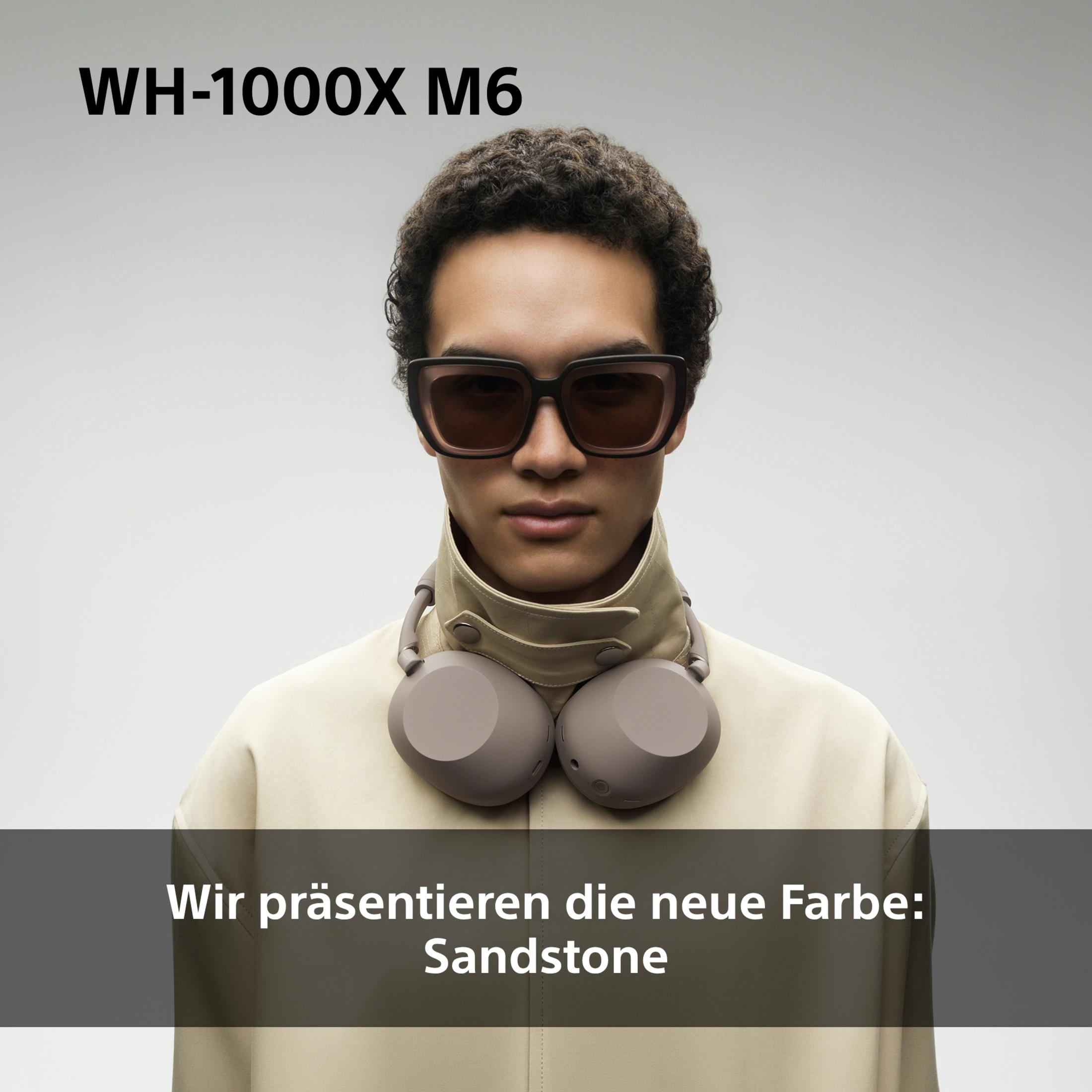 Uomo con cuffie e occhiali da sole, indossa giacca beige. Nuovo colore: Sandstone.