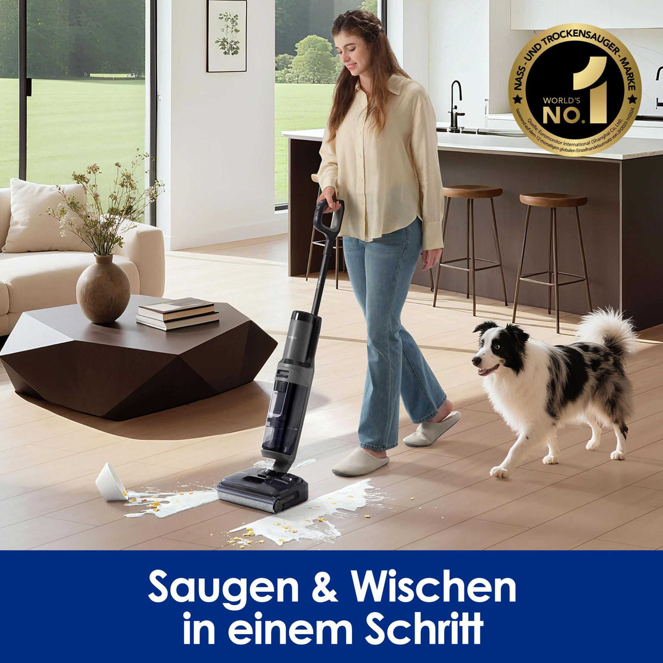 Frau reinigt verschüttete Flüssigkeit mit einem Nass-/Trockensauger, Hund beobachtet.