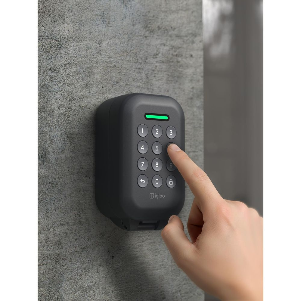 Una mano presiona el número 5 en un teclado digital oscuro montado en una pared gris.