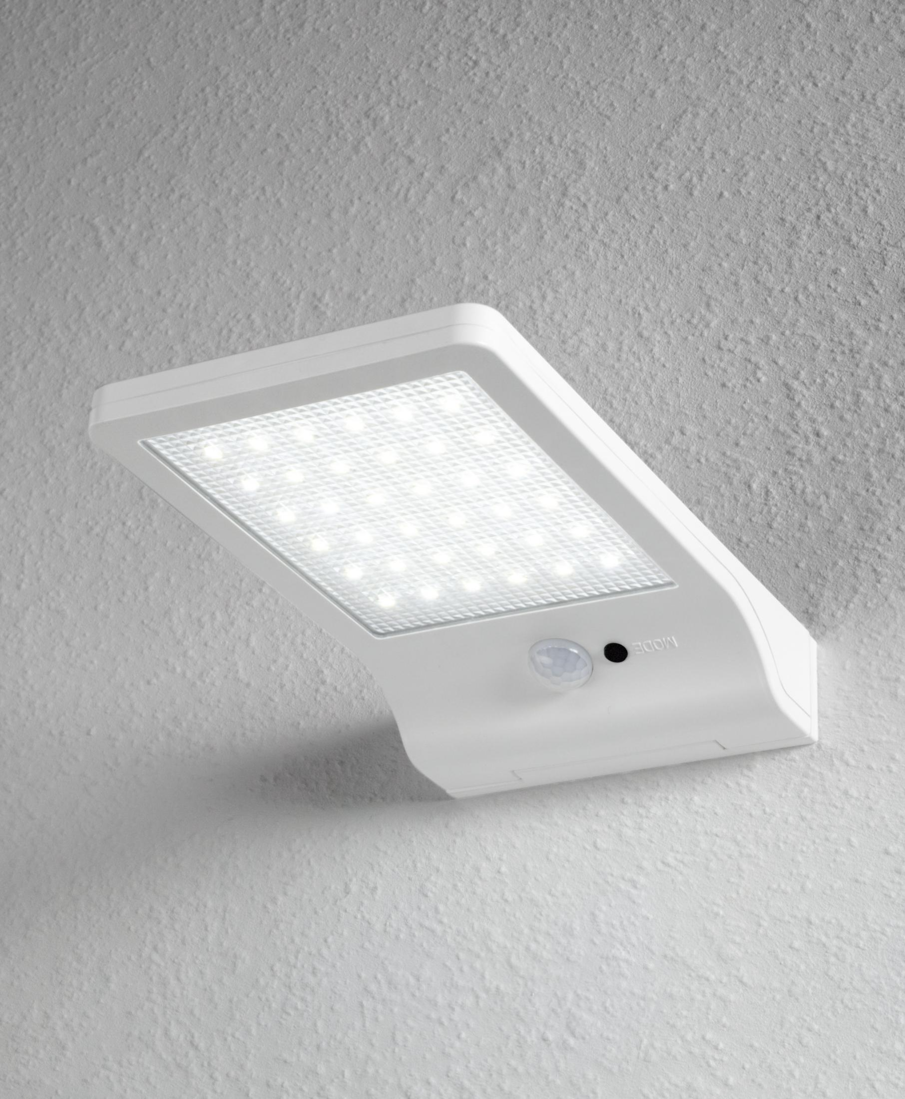 Eine weiße LED-Wandleuchte mit Bewegungsmelder ist an einer strukturierten weißen Wand montiert.