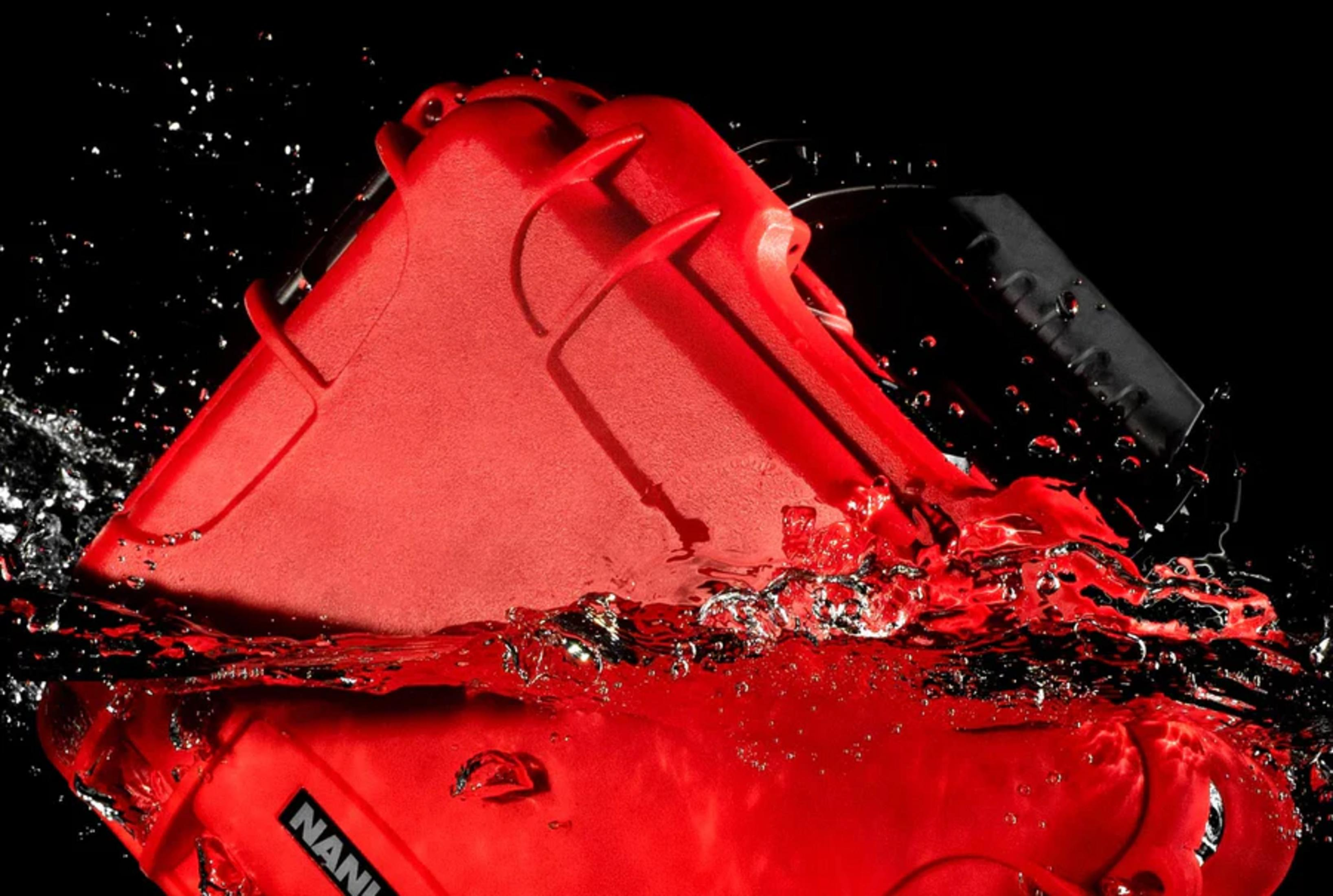 Ein roter Kasten taucht in Wasser ein, mit Spritzern und Blasen.