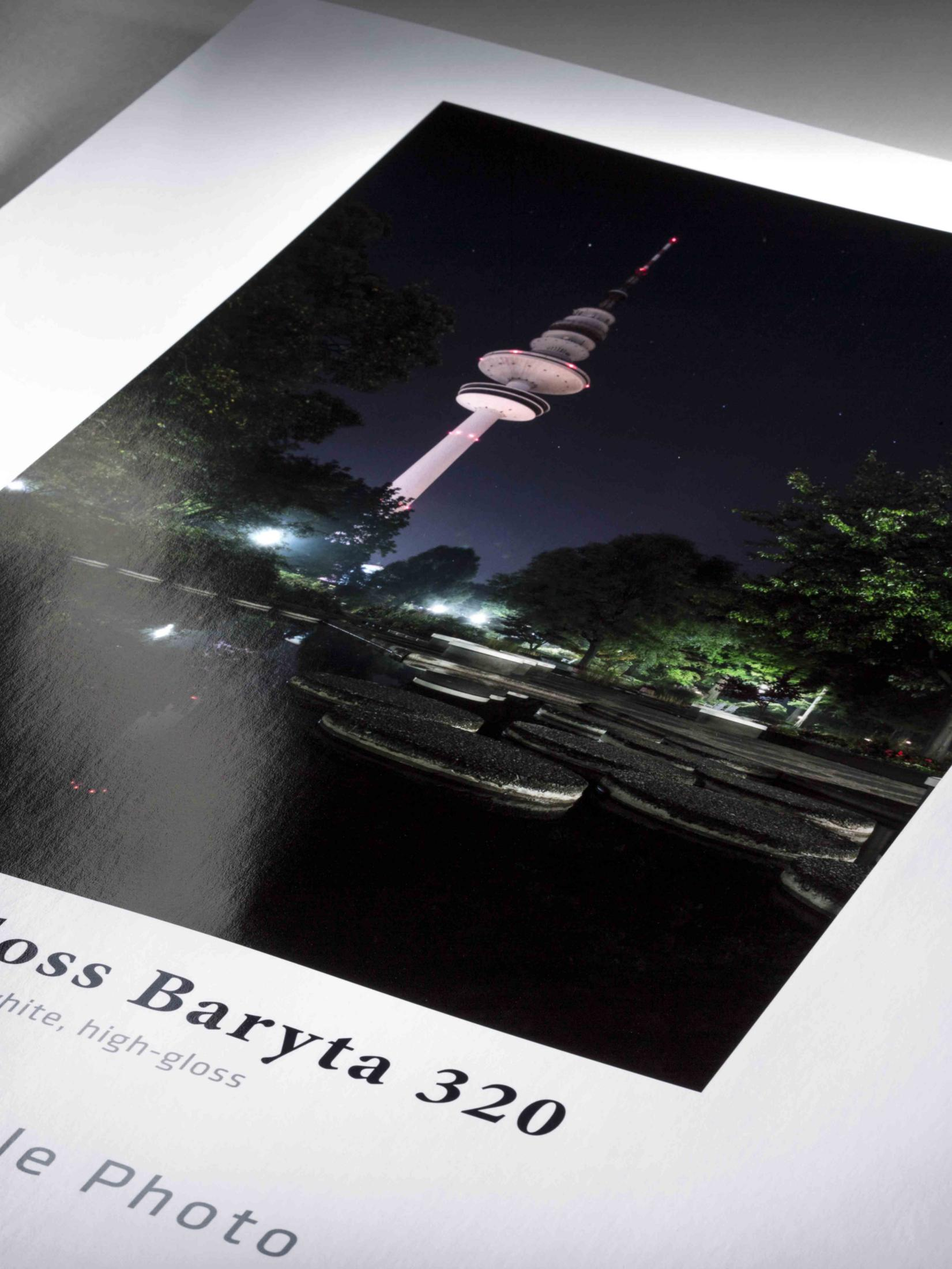 Ein Fernsehturm bei Nacht, beleuchtet mit Lichtern, umgeben von Bäumen und Wasser.